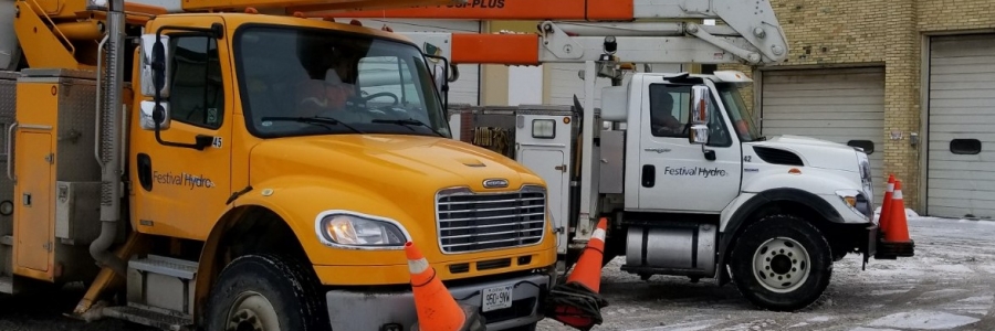 A yellow bucket truck and a white bucket truck emblazoned with the Festival Hydro Logo on the doors