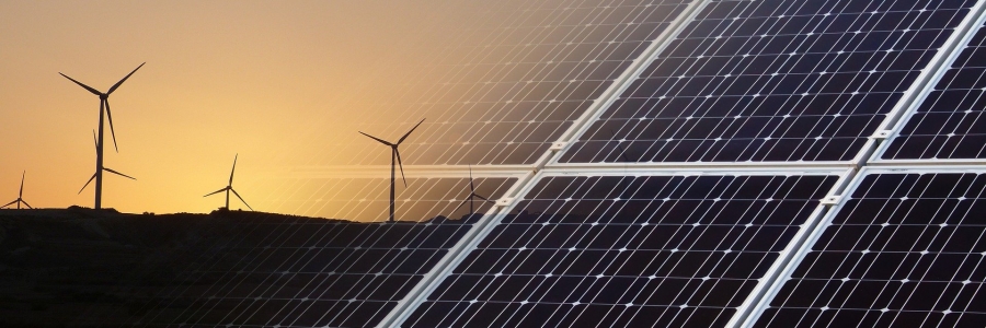 An image of wind turbines at sunset that fades into an image of a solar panel from left to right.