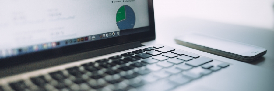 a partial image of a laptop keyboard and screen displaying a blue line graph and a blue and green pie chart. 