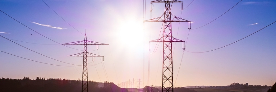 a field of powerlines, with clouds and a blue sky