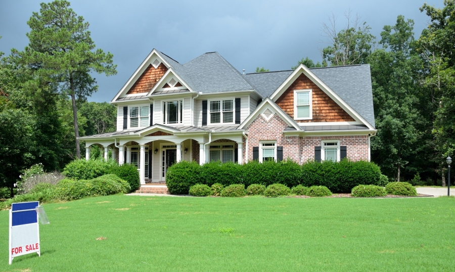 a large house with a gray roof stands among large hedges with a large frontage.