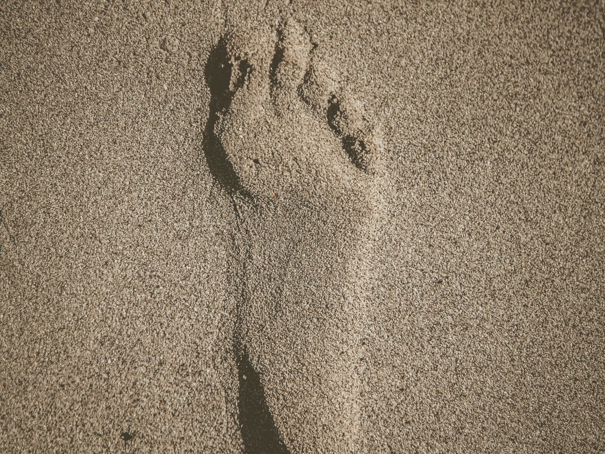 a bare human foot print in brown sand