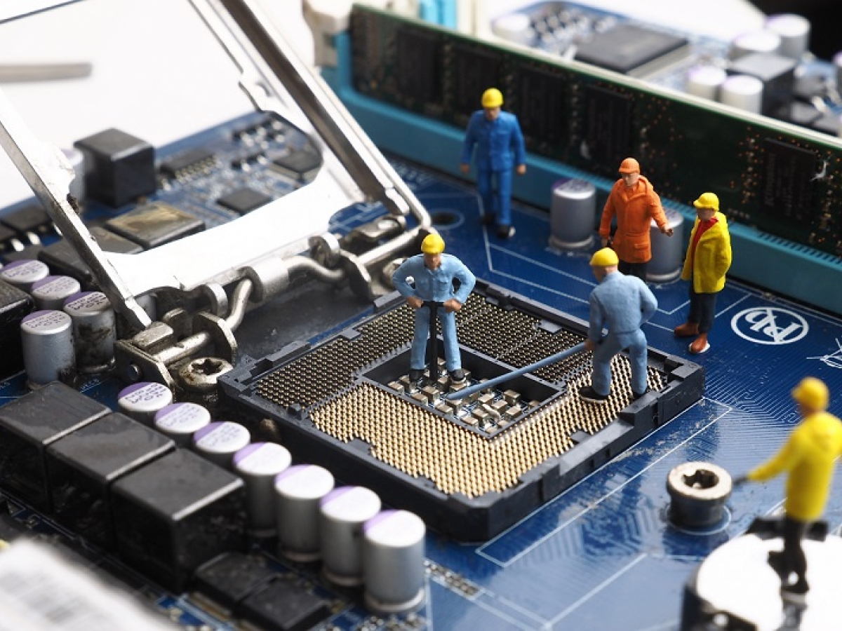 small plastic figurines working on a computer chip